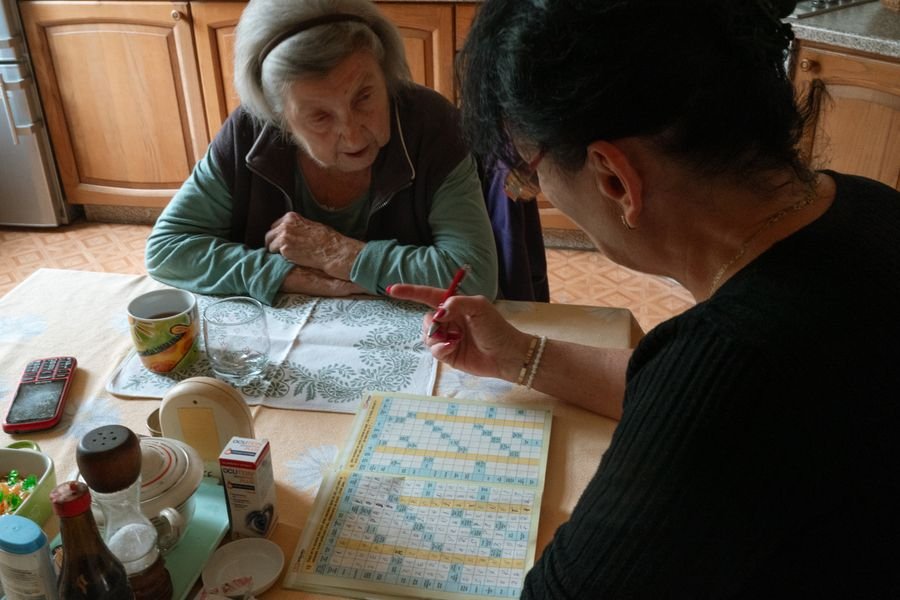 Caregiver preparing medication for an elderly man in his living room