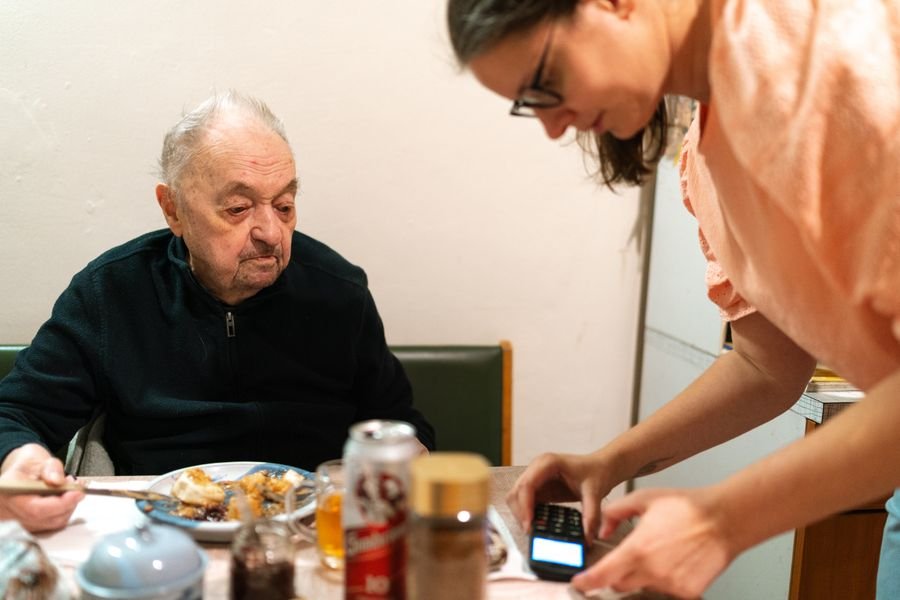 Caregiver assisting a senior gentleman during mealtime